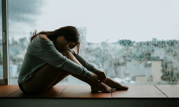 woman in gray long sleeve shirt sitting on window